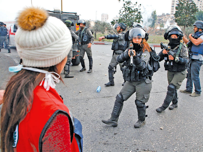 جندية إسرائيلية توجه بندقيتها إلى متظاهرة فلسطينية في بيت ايل بالضفة أمسt(أ ف  ب)