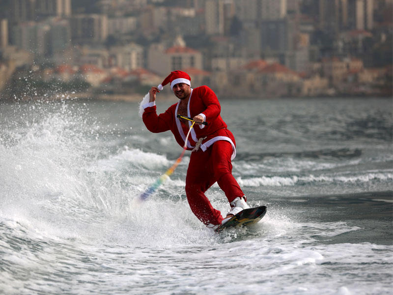 لبناني بثياب سانتا كلوز يتزلّج على الماء في بحر منطقة جونيه أمس t(أ ف ب)