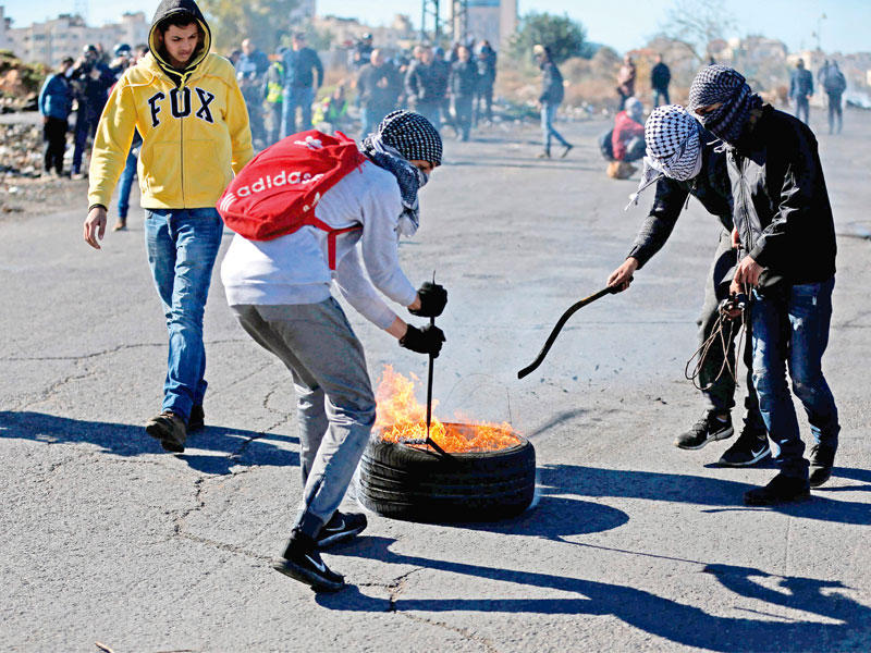 فلسطينيون يغلقون طريقا خلال مواجهات مع القوات الإسرائيلية في الضفة الغربية المحتلة أمس (أ ف ب)