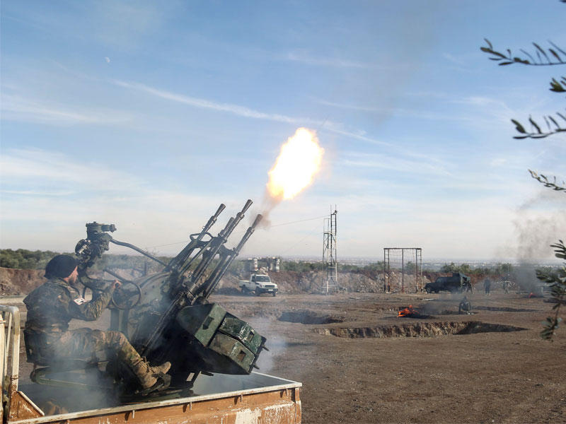 مقاتل في «قسد» أمام شجرة كريسماس في كاتدرائية الأرمن المدمرة في الرقة عاصمة داعش السابقة (أ ف ب)