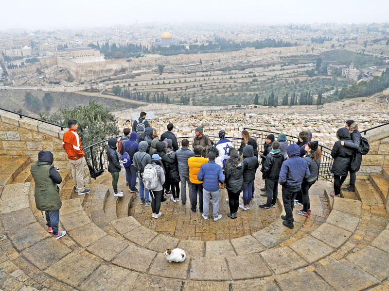 سياح يستمعون أمس إلى شرح على جبل الزيتون المطل على القدس القديمة (رويترز)n