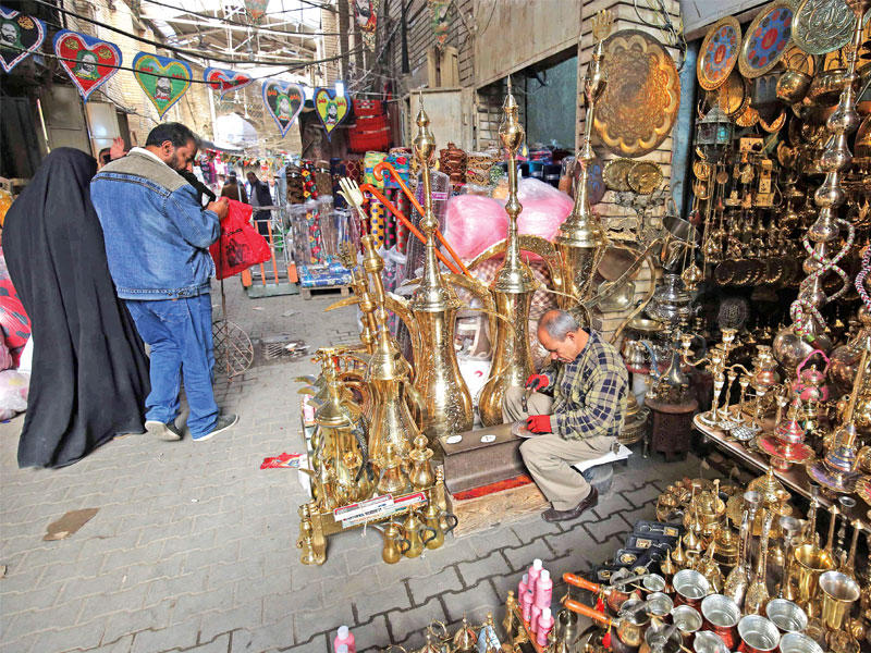 بائع نحاسيات بسوق بغداد القديم ينتظر زبائن أمس(أ ف ب)