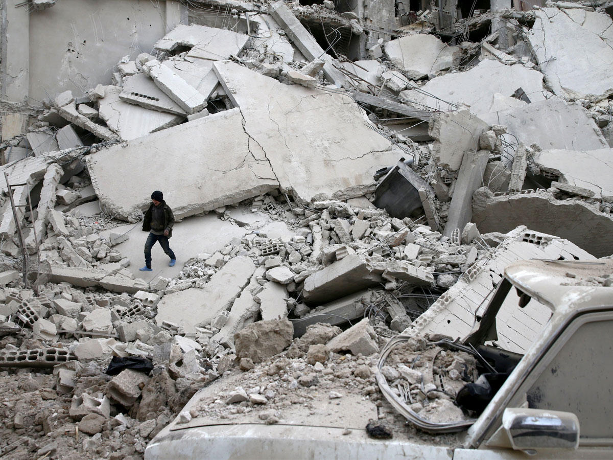 فتى يسير بين ركام مبانٍ تعرضت لغارة في مسرابا بالغوطة الشرقية أمس الأول (رويترز)
