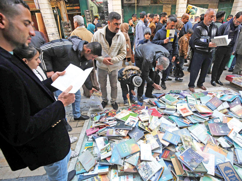 عراقيون يشترون الكتب في شارع المتنبي في بغداد أمس (أ ف ب)