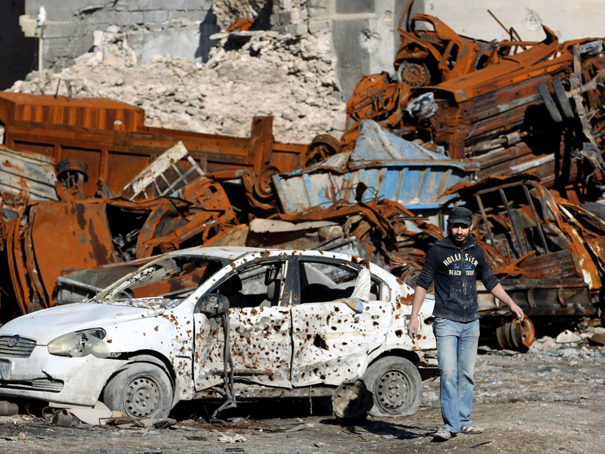 نازح عراقي أمام حطام سيارات لدى عودته إلى الموصل قبل أيامt(أ ف ب)