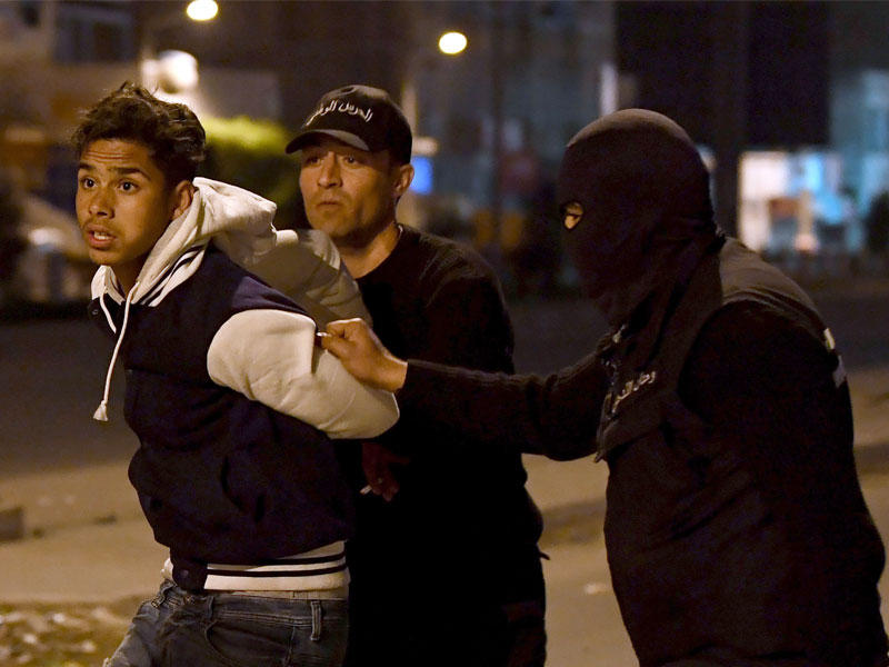 عنصران أمنيان يعتقلان أحد المتظاهرين في منطقة التضامن التونسية مساء أمس الأول(أ ف ب)