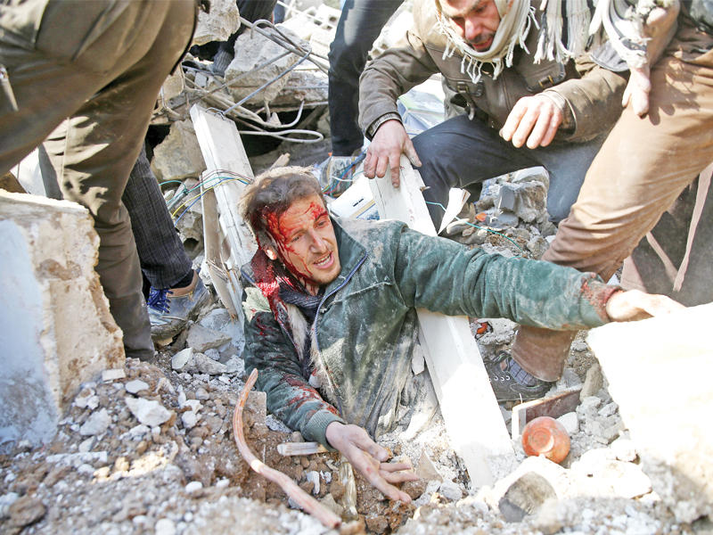 مسعفون ينتشلون شاباً حياً من تحت أنقاض منزل في منطقة الصقبة دمّرته طائرة سورية (رويترز)