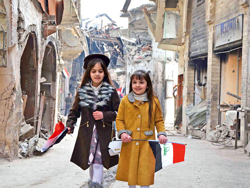 فتاتان عراقيتان تحملان العلم العراقي خلال مراسم إعادة فتح سوق باب السراي في مدينة الموصل القديمة في 11 يناير الجاري 