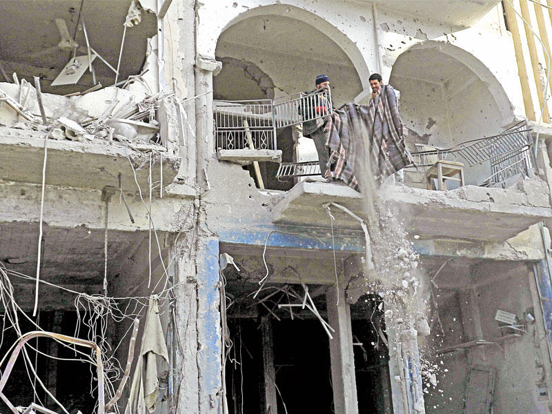 سوريان يعملان في ترميم مبانٍ مدمرة  بالرقة أمس الأول (أ ف ب)