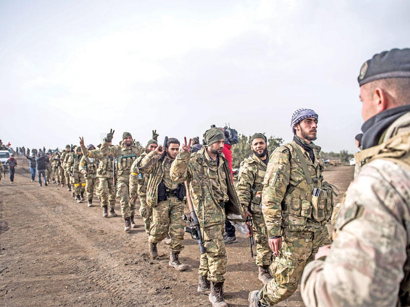 جندي تركي يشرف على مقاتلين سوريين موالين لأنقرة يتجهون إلى المعارك أمس (أ ف ب)