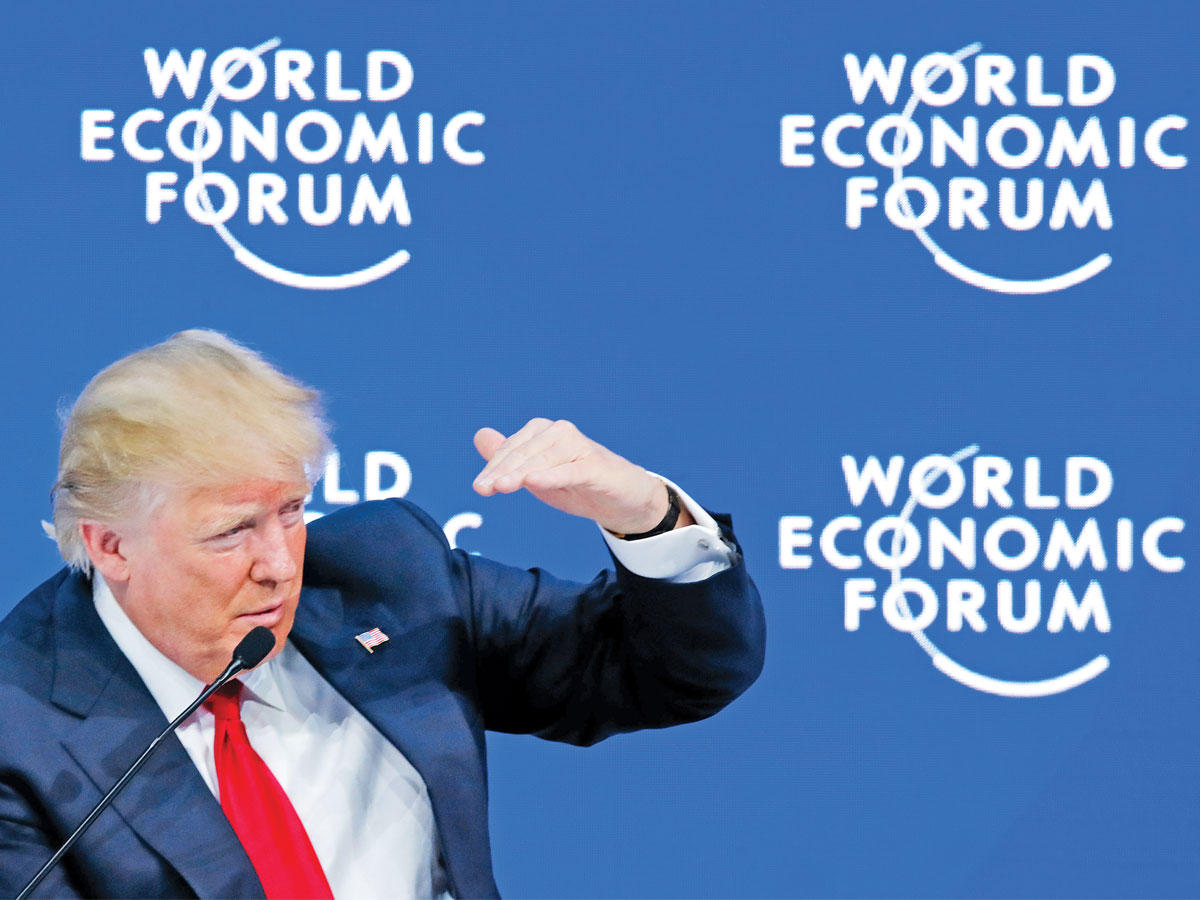 ترامب يدقق في لافتات منتدى دافوس أمس (رويترز)