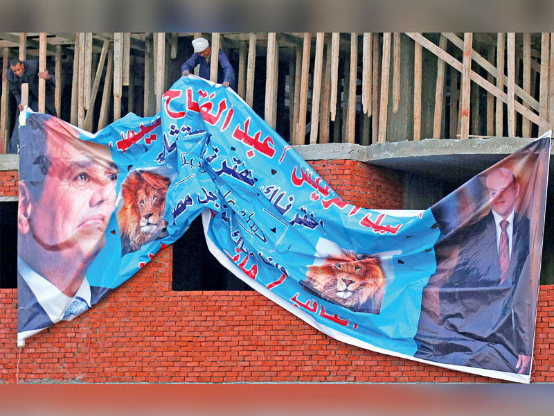 عمال يعلقون يافطة ضخمة داعمة للسيسي في القاهرة أمس الأول   (رويترز)