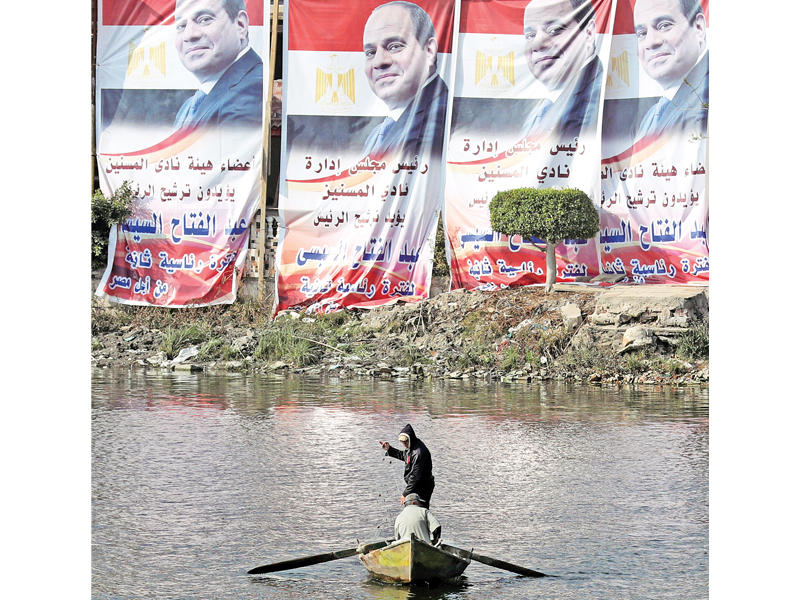 مصري في النيل يمر أمام ملصقات ضخمة للسيسي أمس (رويترز)