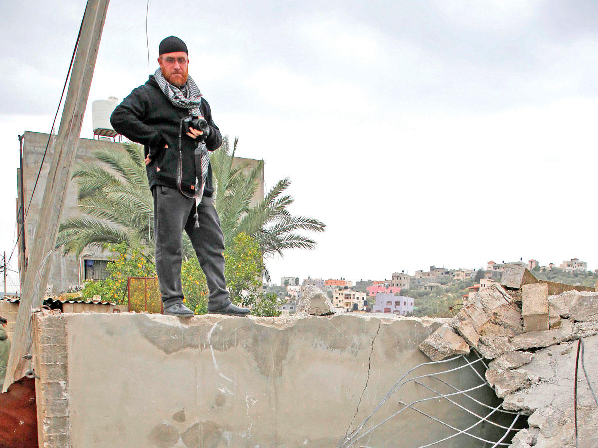 فلسطيني فوق أنقاض المنزل الذي هدّمته اسرائيل وكان يحتمي في داخله أحمد جرار قبل قتله (أ ف ب)