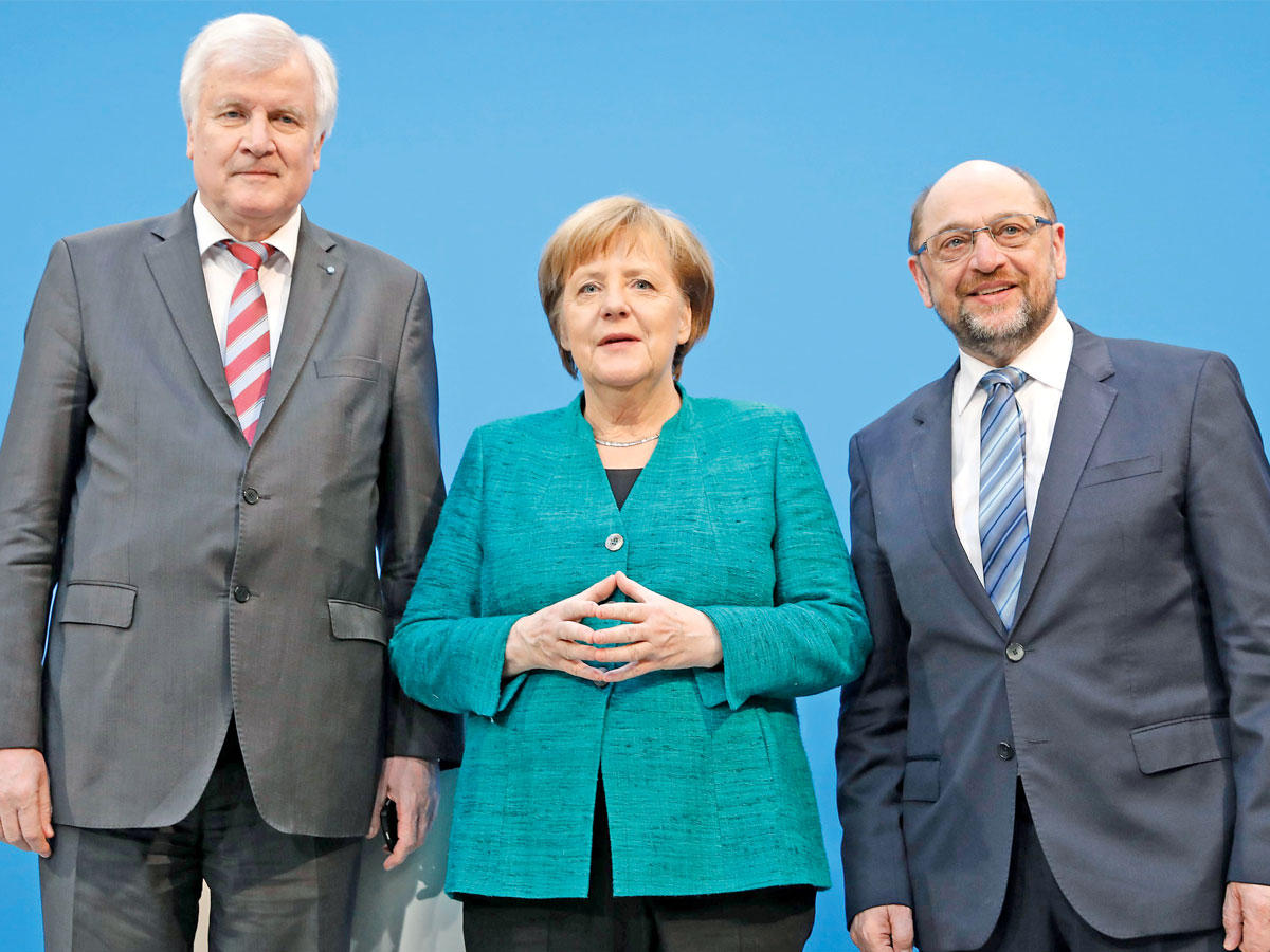 ميركل تتوسّط شولتس وزيهوفر بعد الإعلان عن تشكيل الحكومة الجديدة (رويترز)