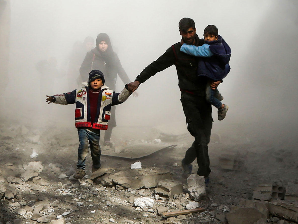 سوري يفر بأسرته من غارات النظام على بلدة جسرين بالغوطة أمس  (أ ف ب)