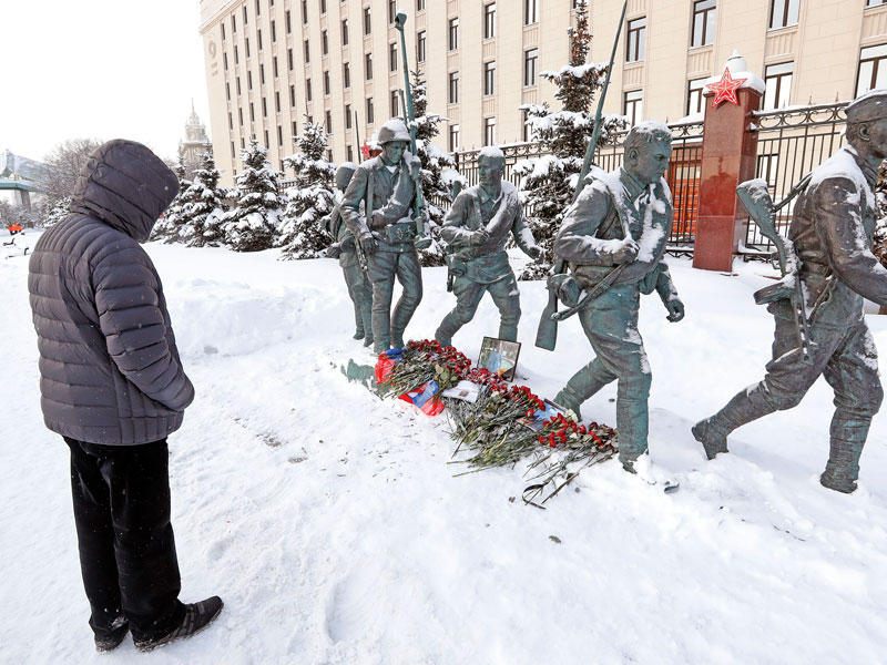 روسي يقف دقيقة صمت امام نصب تذكاري للجنود الروس القتلى امام وزارة الدفاع في موسكو حيث وضعت صورة للطيار الروسي رومان فيليبوف الذي قتل بعد إسقاط طائرته في سورية (إي بي أيه)