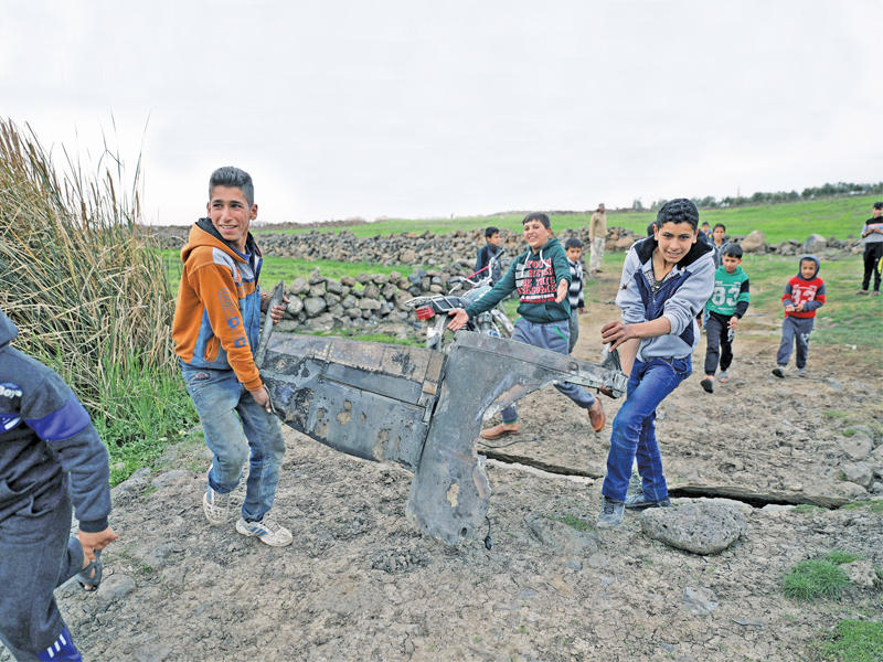 صبية يحملون جزءاً من صاروخ سقط في القنيطرة أمس (رويترز)