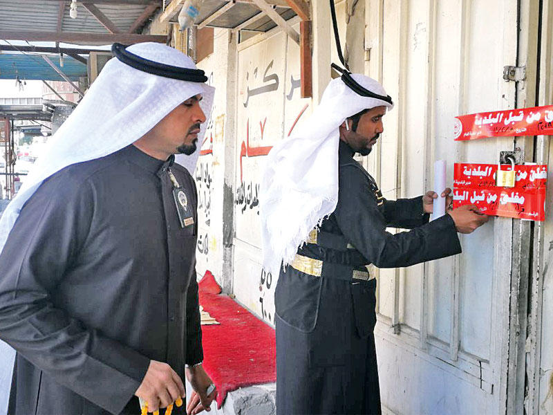 موظفان بالبلدية خلال وضع ملصق الإغلاق