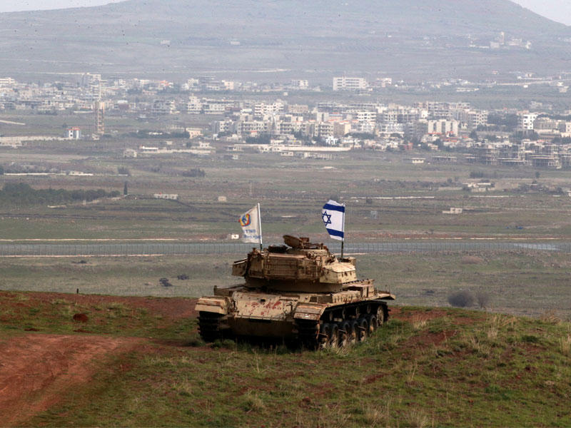 دبابة قديمة عليها علم إسرائيل مقابل قرية مجدل شمس الدرزية في مرتفعات الجولان  (رويترز)