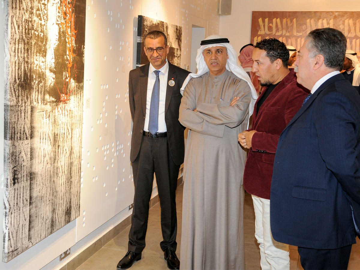 اليوحة مستمعاً إلى شرح الخطاط كريم جباري بحضور عدد من زوار المعرض