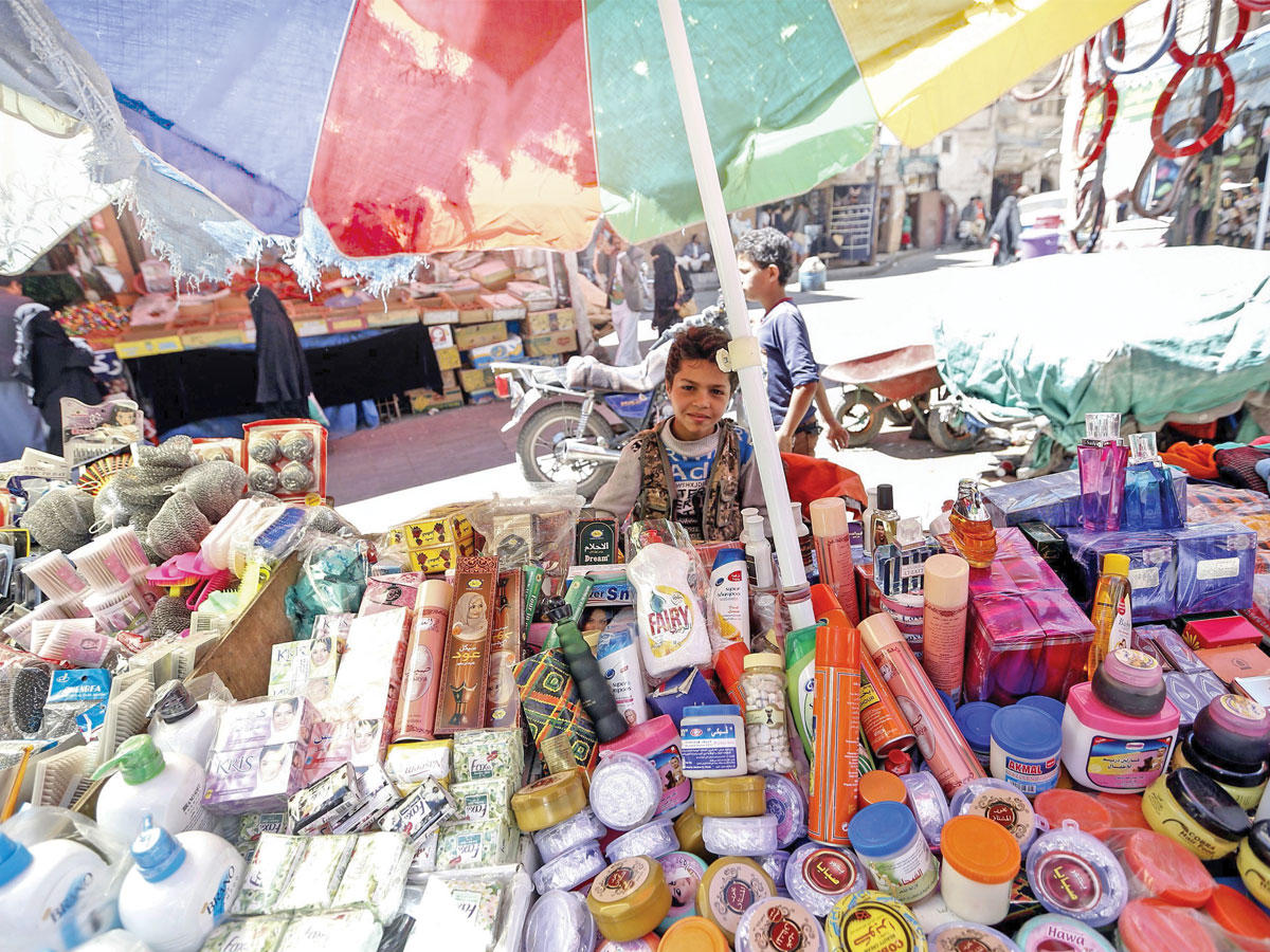 ولد يمني يجلس بين بضاعة معروضة للبيع في أحد أسواق صنعاء القديمة أمس الأول (ا ف ب)