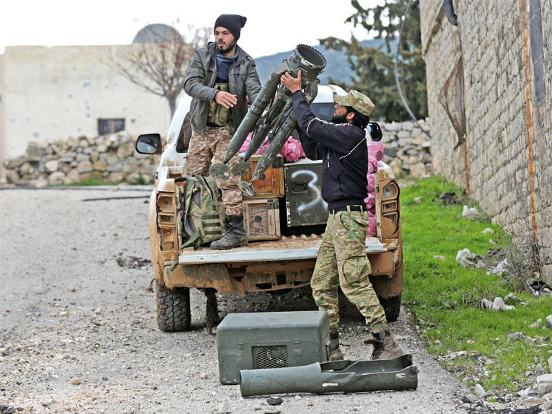 مقاتلان مدعومان من أنقرة يجهّزان قاعدة صواريخ في عفرين أمس (رويترز)
