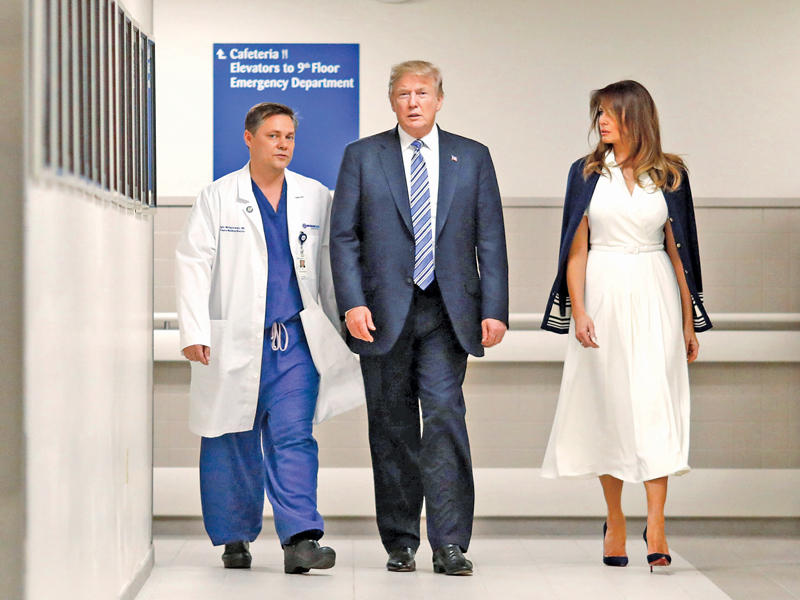 ترامب متوسطاً السيدة الأولى وأحد الأطباء خلال زيارته جرحى الاعتداء على مدرسة فلوريدا أمس الأول (رويترز)