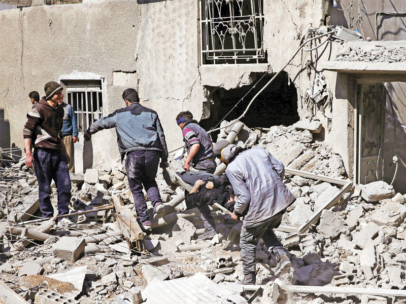 سوريون يجلون مصاباً من تحت منزله المدمر في حمورية المحاصرة t(رويترز)