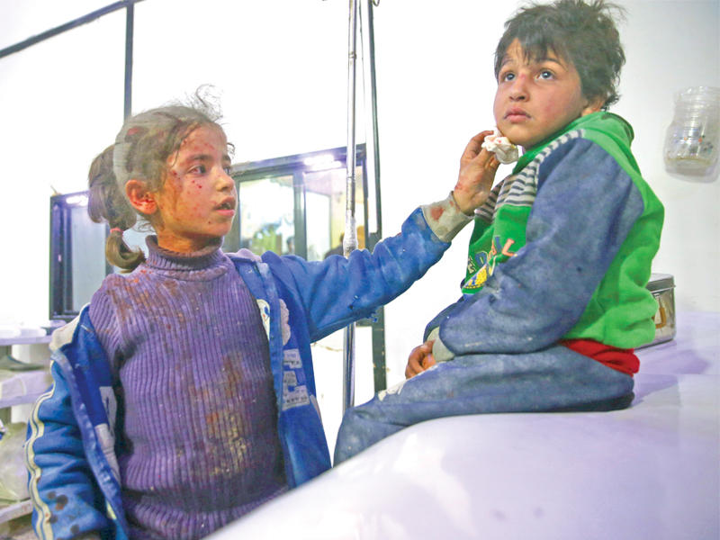 طفلة مصابة تمسح دماء شقيقها في مستشفى دوما أمس الأول  (رويترز)