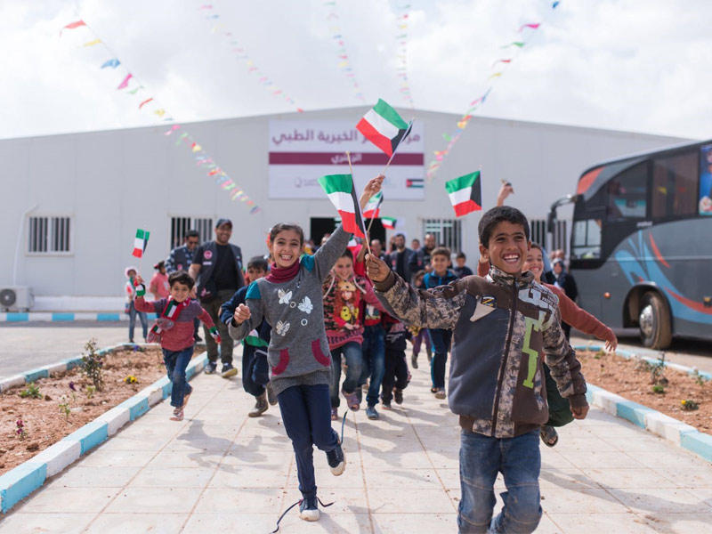 أطفال سوريون يحملون علم الكويت خلال خروجهم من مركز العلاج الطبي