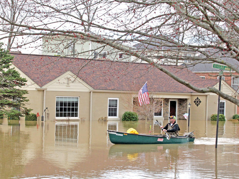 أميركي يتنقل بالقارب في شوارع لويسفيل بسبب الفيضانات أمس الأول (رويترز)