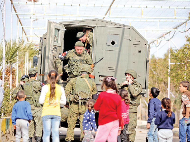 أطفال يتابعون وصول جنود روس إلى مخيم الوافدين في دمشق أمس (رويترز)