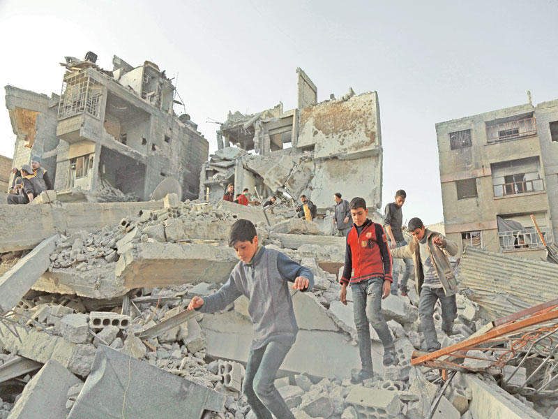 صبية على أنقاض منازلهم المدمرة في الغوطة أمس الأول (أ ف ب)