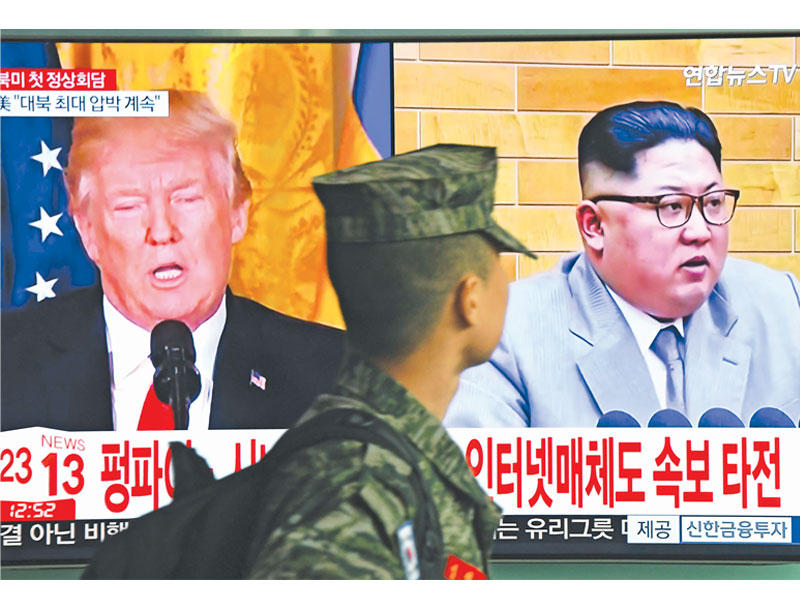 جندي كوري يمرّ أمام تلفزيون يعرض خبر قمة ترامب وكيم بمحطة سيول أمس (أ ف ب)