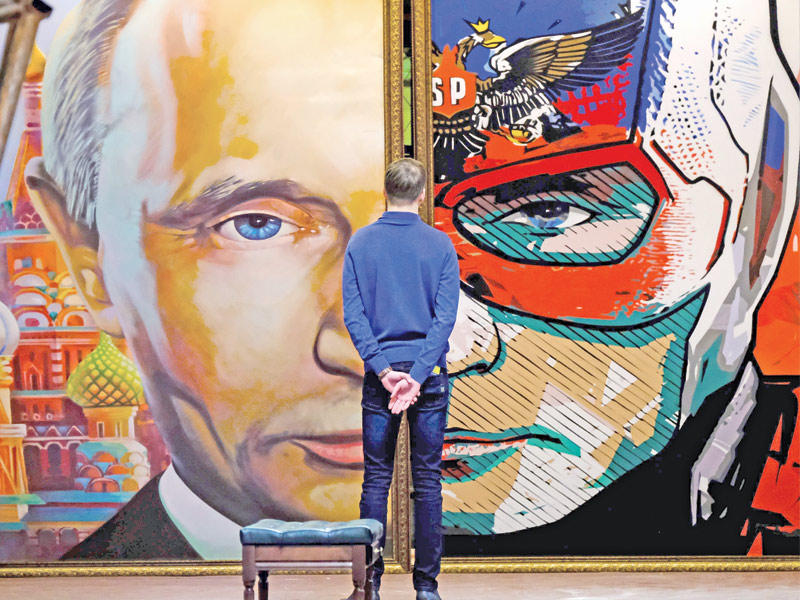  رجل يقف أمام صورة لبوتين تظهر نصف وجهه بـ «سوبر بوتين» في أحد متاحف موسكو (أ ف ب)
