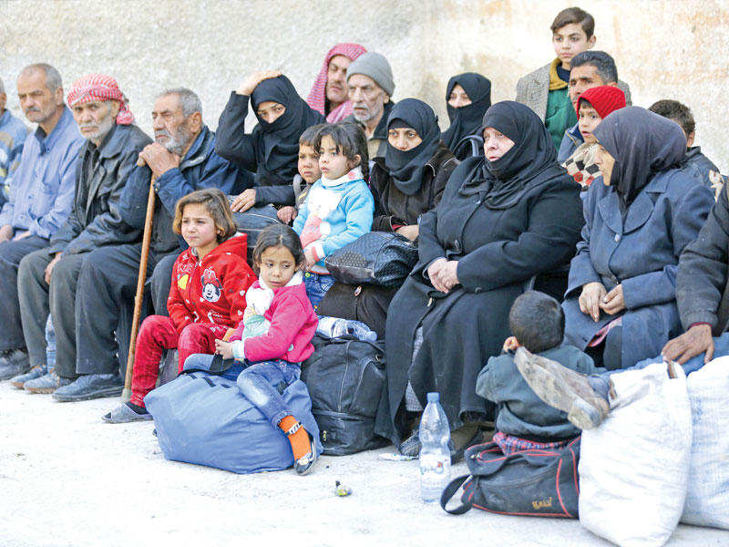 أطفال ونساء ومسنون في ساحة مدرسة ينتظرون الخروج من معبر الوافدين على مشارف دمشقt(أ ف ب)
