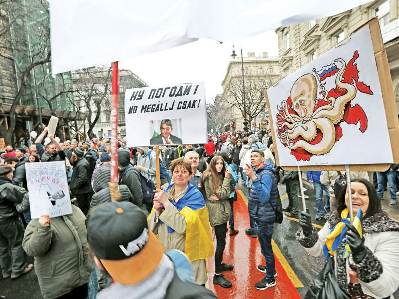 متظاهرون يرفعون صورا ولافتات معادية لبوتين في بودابست أمس (أ ف ب)n