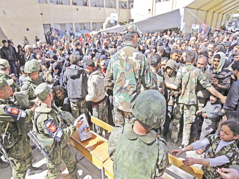 نازحون من الغوطة يتلقون مساعدات من القوات الروسية في عدرا أمس (أ ف ب)