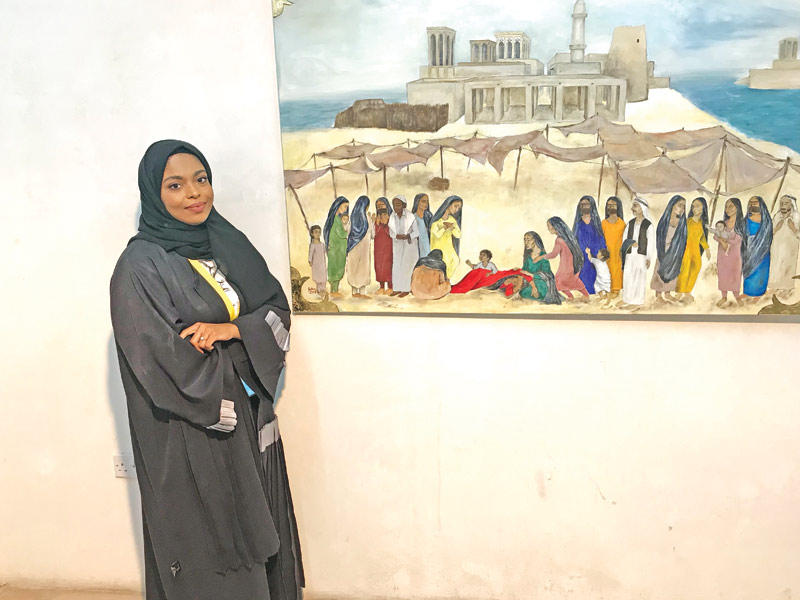 فاطمة محمد أمام إحدى لوحاتها 