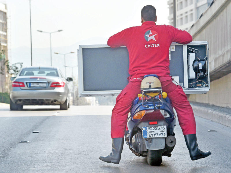 رجل ينقل ثلاجة على دراجته النارية في بيروت  (اي بي آي)