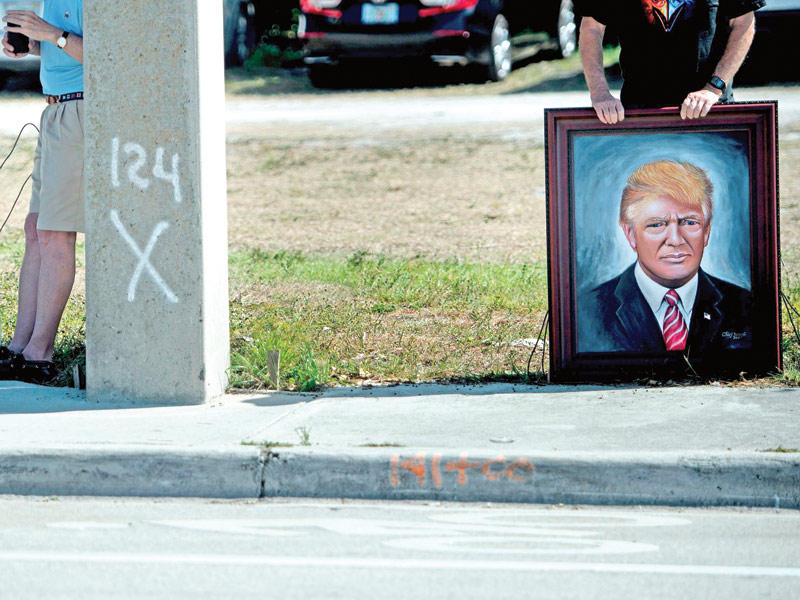 أميركي يحمل صورة لترامب في بالم بيتش قبل ايام (أ ف ب)