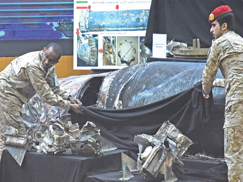 عسكريان ينقلان شظايا صواريخ حوثية اعتُرضت بأجواء المملكة خلال مؤتمر عقده التحالف في الرياض أمس الأول t(أ ف ب)