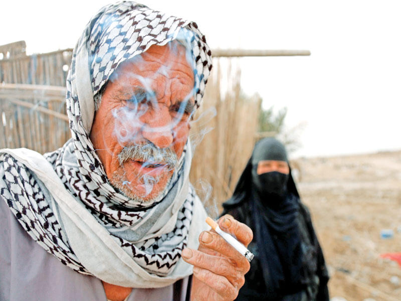عراقي ينفث دخان سيجارته في محافظة الديوانيةtt(أ ف ب)