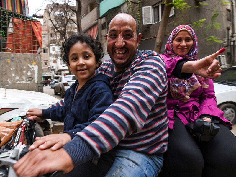 أسرة مصرية على «موتسيكل» بعد المشاركة بالانتخابات الرئاسية في القاهرة أمس (أ ف ب)