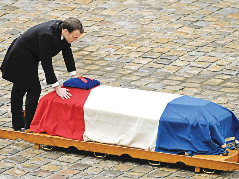 ماكرون منحنياً فوق نعش برترام في ثكنة «ليزينفاليد» في باريس أمس t(أ ف ب)