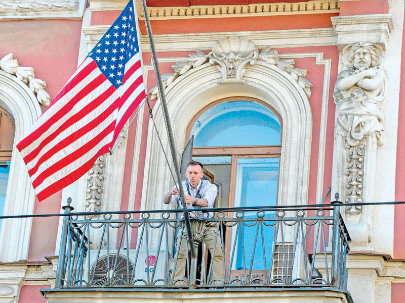 موظف يرفع علم بلاده على القنصلية الأميركية في سان بطرسبورغ أمس (أ ف ب)