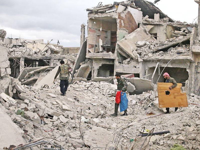 سوريون وسط الركام داخل مدينة دوما أمس الأول    (رويترز)