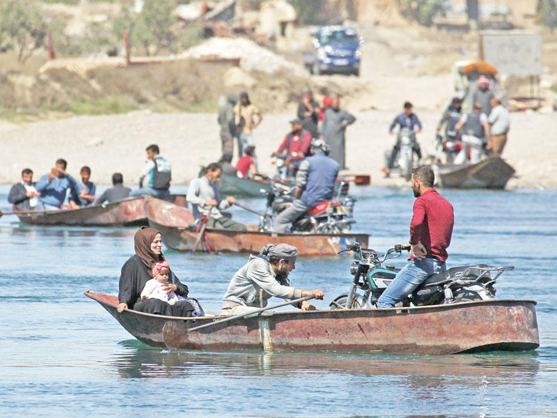 سوريون يعبرون نهر الفرات على قوارب في الرقة أمس (رويترز)