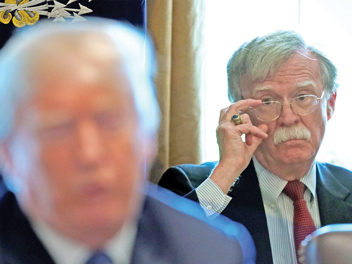 بولتون خلف ترامب أمس خلال اجتماع في البيت الأبيض (رويترز)